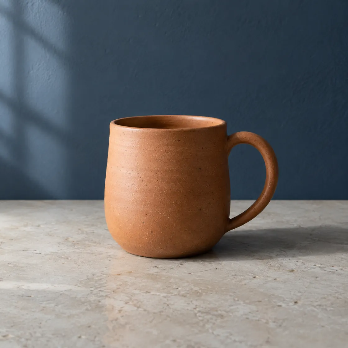 Original terracotta mug photograph against a slate-blue wall.